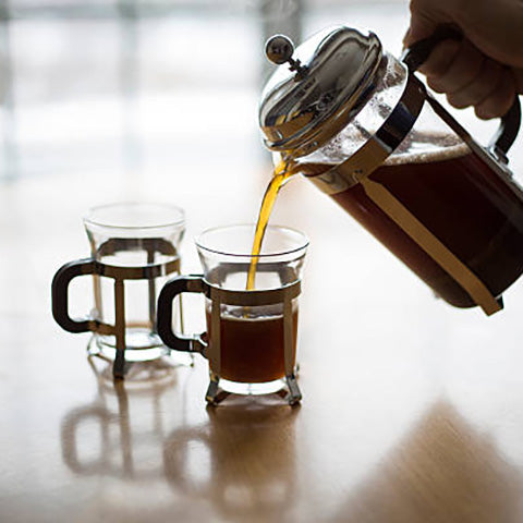 French Press pot pouring coffee into coffee mugs