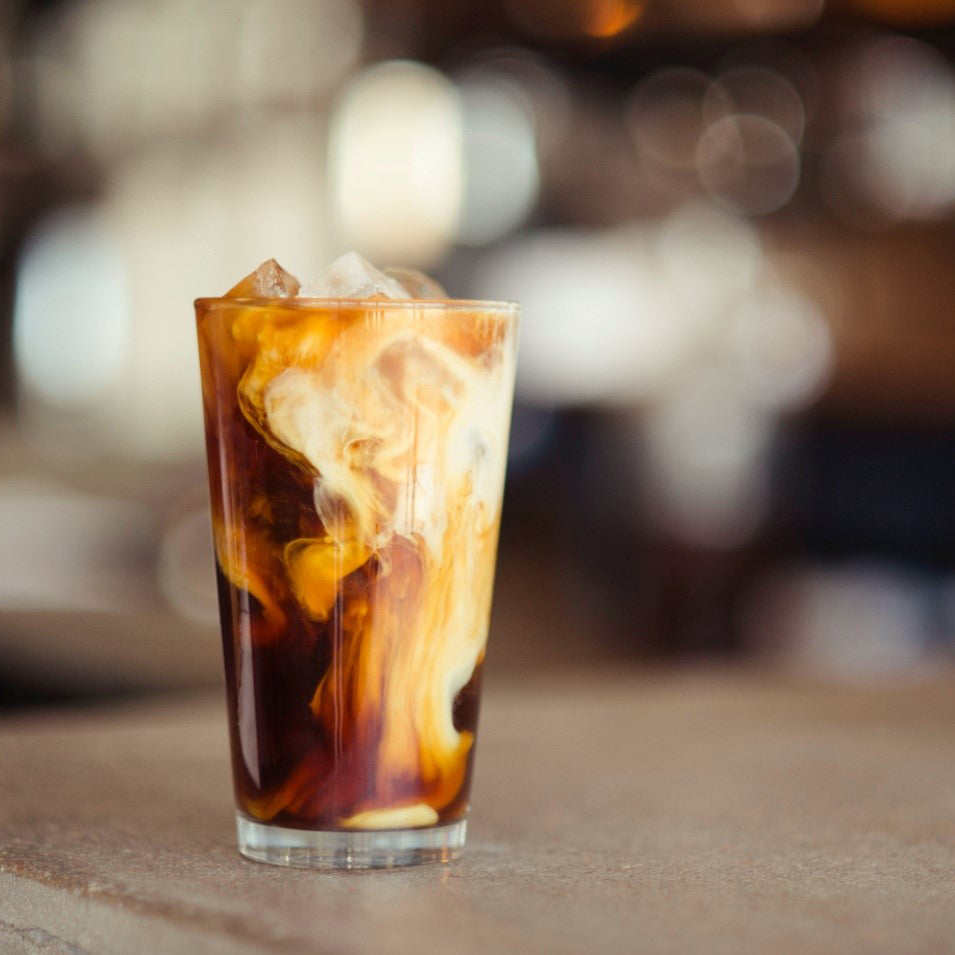 glass filled with iced latte on a table top